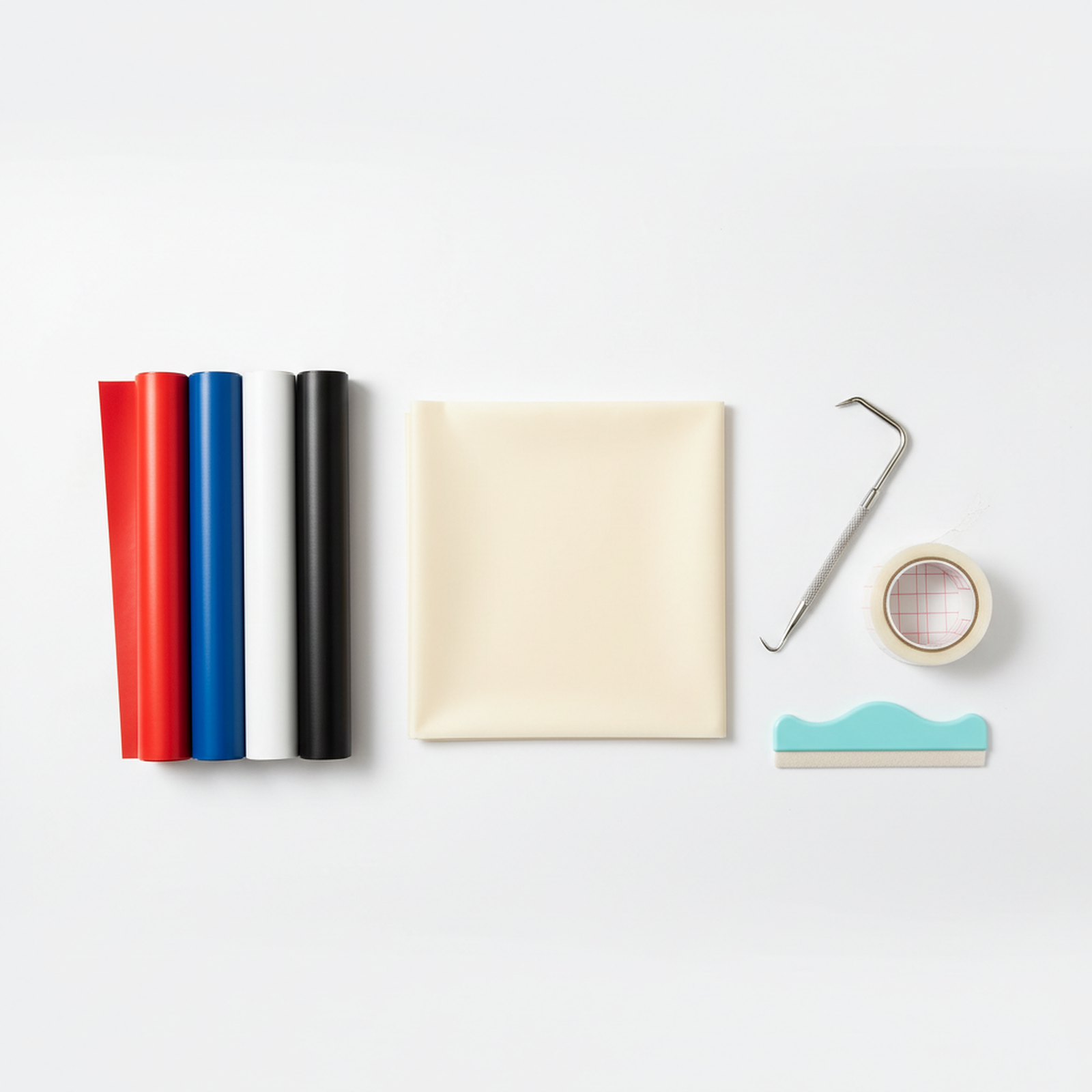 Heat press supplies flat lay with PTFE sheet, HTV vinyl rolls, and weeding tools